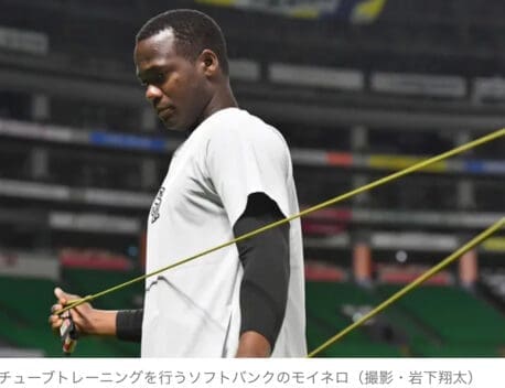 バドミントン選手が練習でレジスタンスバンドを使用している屋内スポーツアリーナの写真。