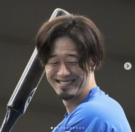 野球選手がバットを持ち、喜びを表現する写真。
